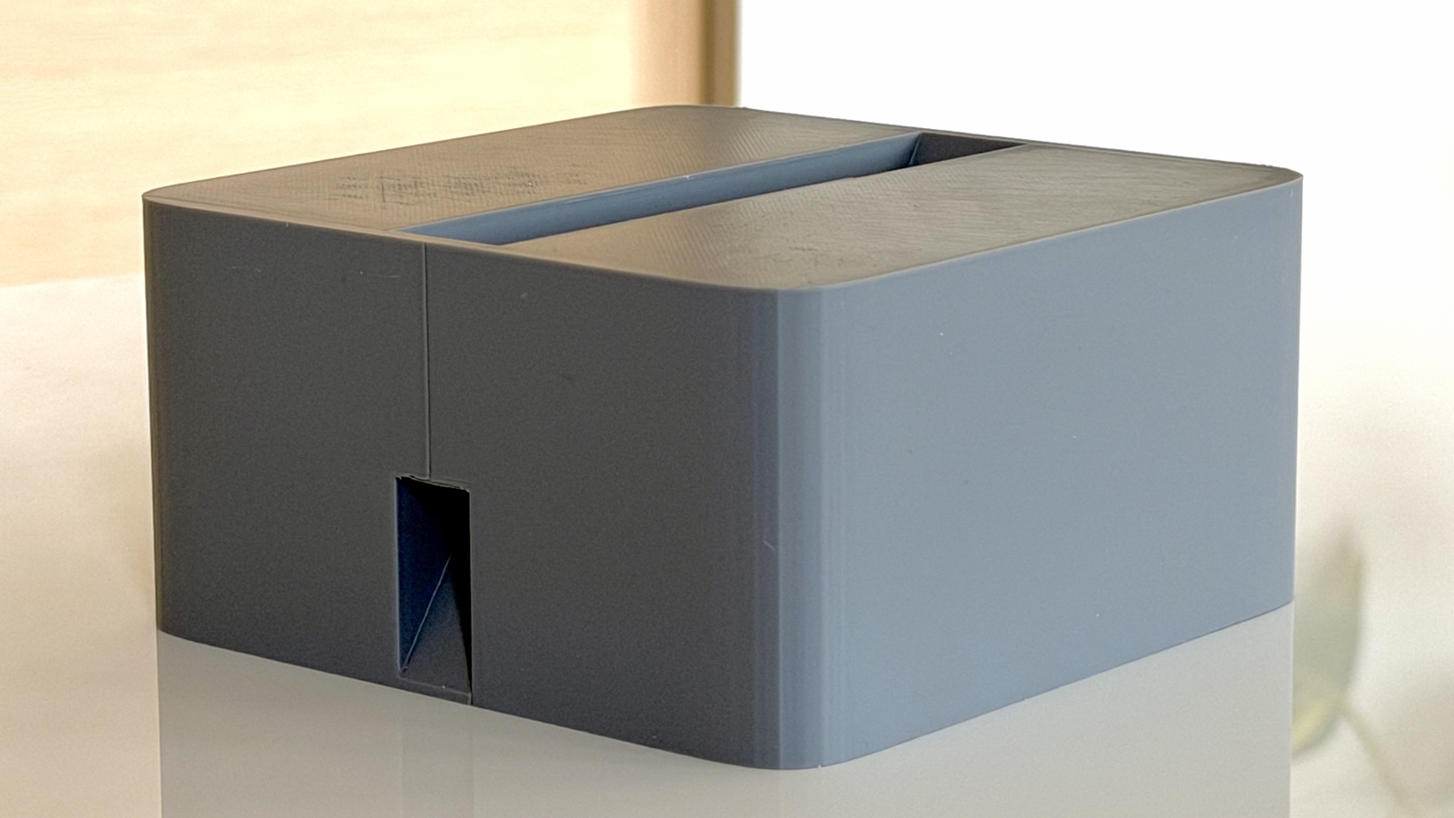 A Cubistand on its own, three-quarter angle, showing the laptop slot across the top and a small cable pass-through on the front